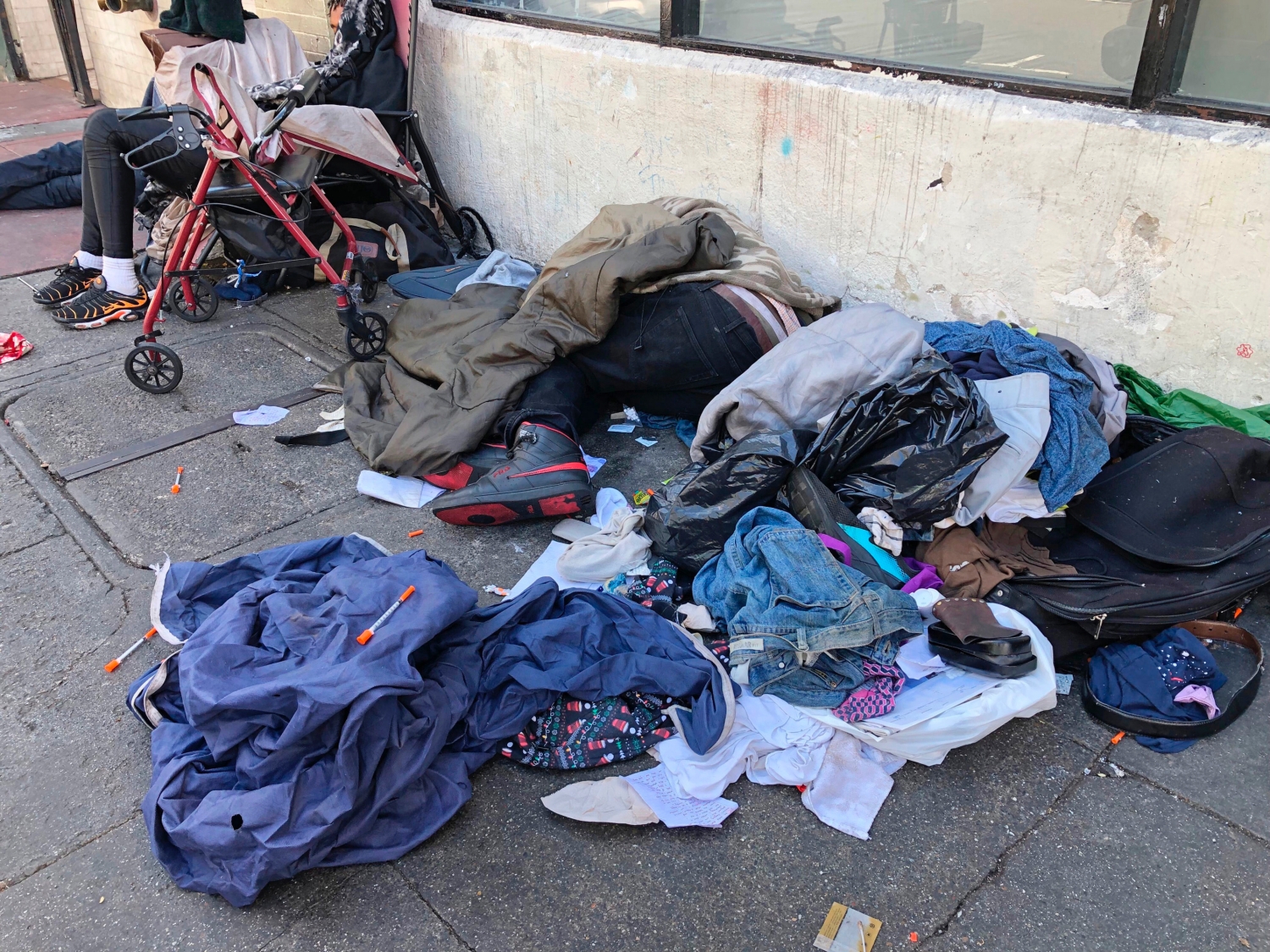 Sleeping people, discarded clothes and used needles are seen on a street in the Tenderloin neighborhood in San Francisco on July 25, 2019. (Janie Har/AP Photo)