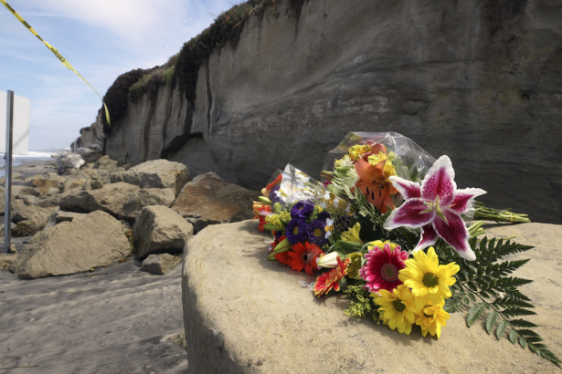 A bouquet of flowers are placed on some of the sand rock debris from Friday's bluff collapse, which killed three people, near the Grandview beach access stairway in Leucadia in Encinitas, California, on Aug. 3, 2019. (Hayne Palmour IV / San Diego Union-Tribune)