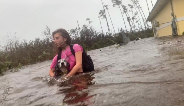 Julia Aylen wades through waist deep water carrying her pet dog as she is rescued from her flooded home during Hurricane Dorian in Freeport, Bahamas, on Sept. 3, 2019. (Tim Aylen/AP Photo)