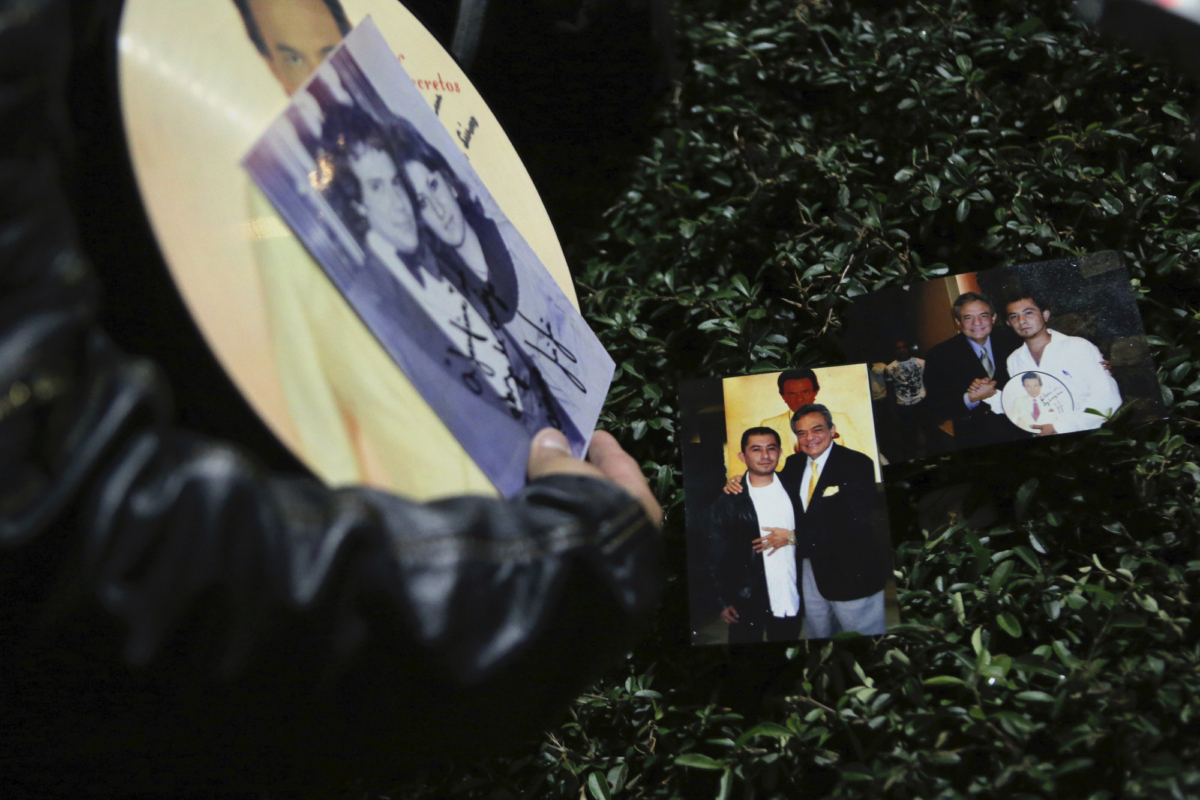 Christian Pacheco displays personal photos of his encounters with Jose Jose as fans mourn his death at Jose Jose's statue in Mexico City, on Sept. 28, 2019. (Anthony Vazquez/AP Photo)