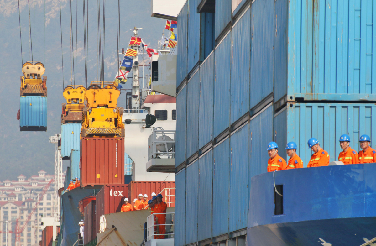 Workers look at cranes lifting containers onto cargo vessels at a port in Yantai, Shandong Province, China on Oct. 17, 2019. (Reuters)