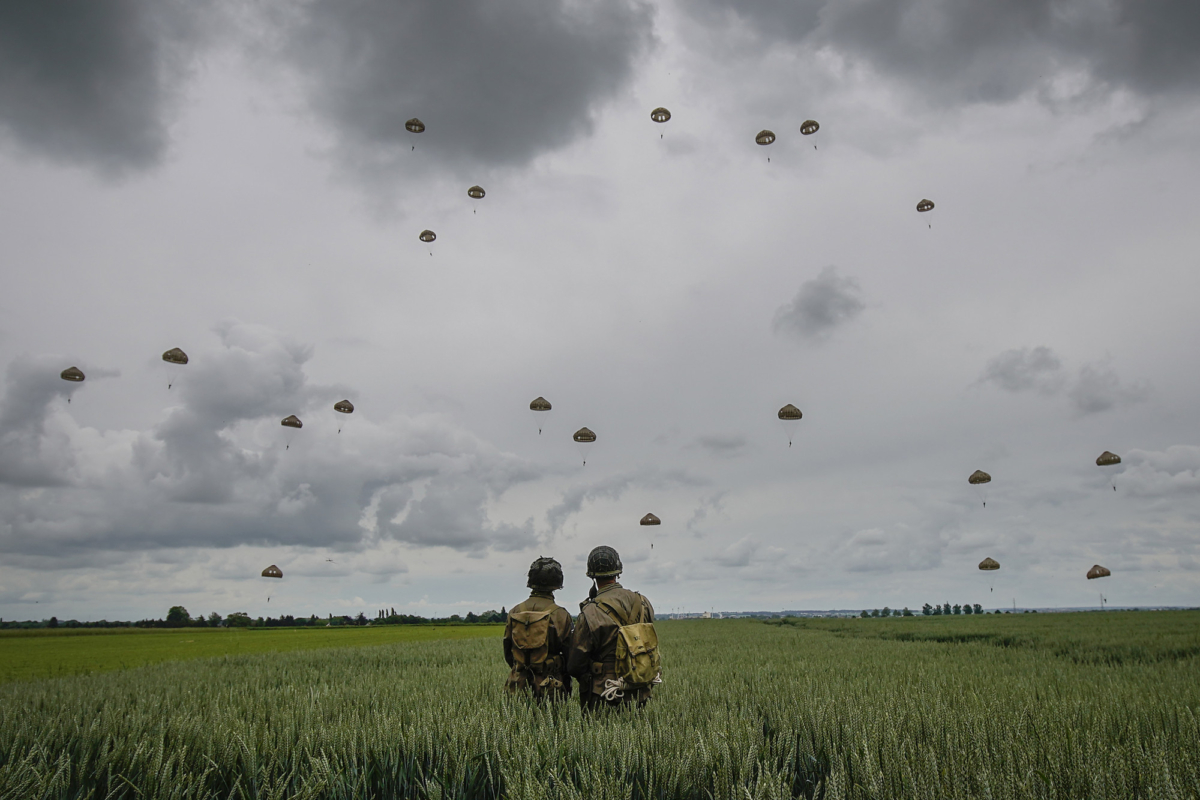Performers look on as paratroopers take part in a parachute drop in a file photo taken on June 5, 2019. (Photo by Christopher Furlong/FILE via Getty Images)