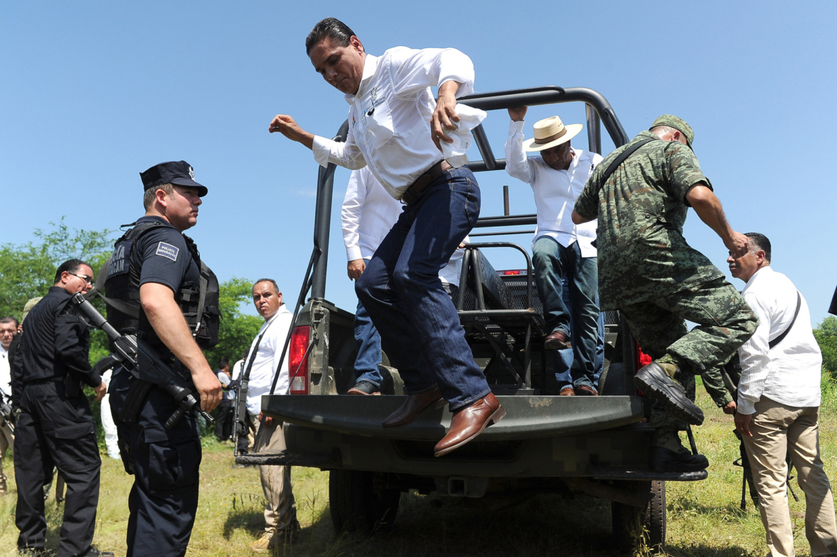 The Governor of the state of Michoacan, Silvano Aureoles (C) jumps from the back of a military utility car after making a speech in El Chauz, Michoacan State, Mexico on Sept. 7, 2016. (Pedro Pardo/AFP/Getty Images)