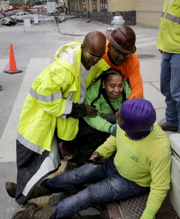 Workers are helped after a large portion of a hotel under construction suddenly collapsed in New Orleans, La., on Oct. 12, 2019. (Scott Threlkeld/The Advocate via AP)