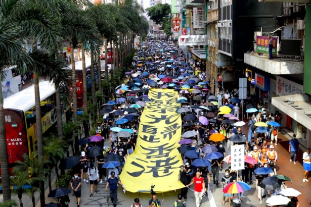 Protesters walk next to a banner with the words "May Glory return to Hong Kong" in Hong Kong on Oct. 5, 2019. (AP Photo/Vincent Thian)