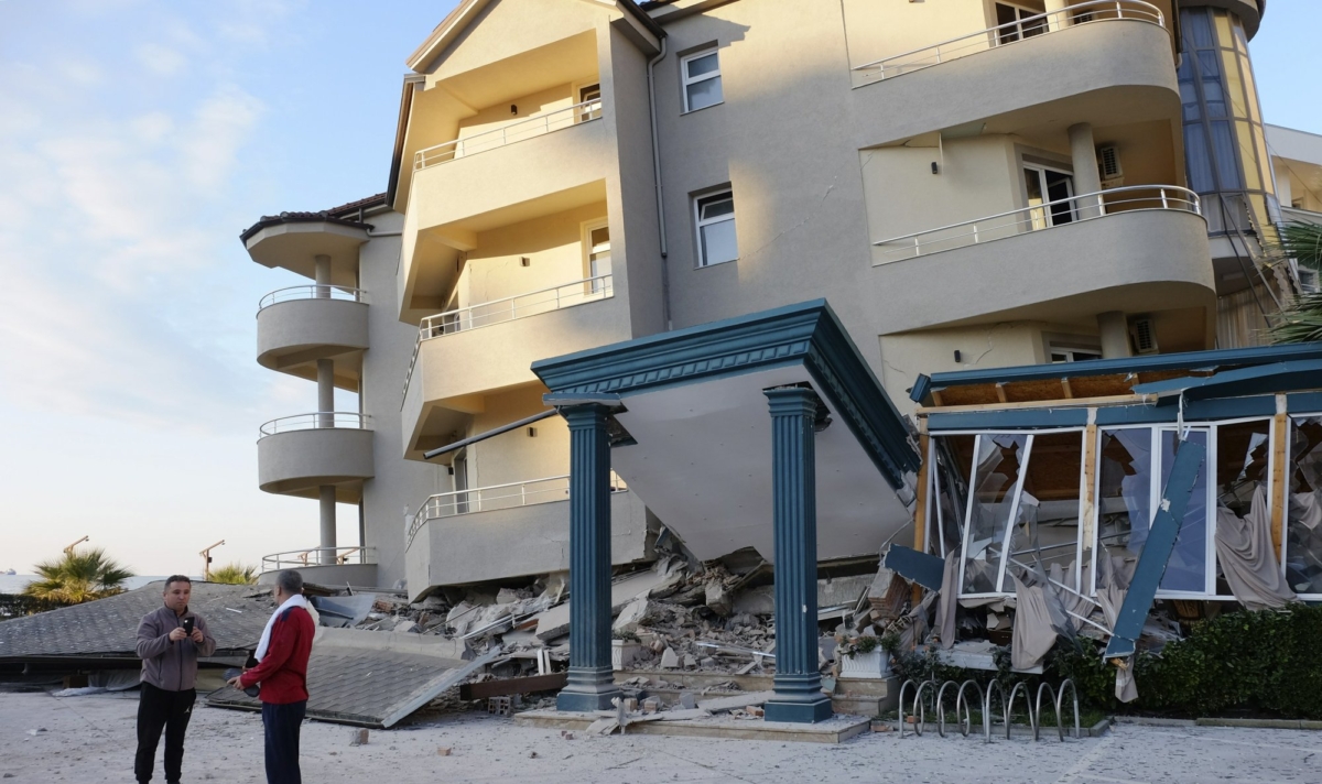 People stand next to a damaged building after a magnitude 6.4 earthquake in Durres, western Albania on Nov. 26, 2019. (Hektor Pustina/AP Photo)
