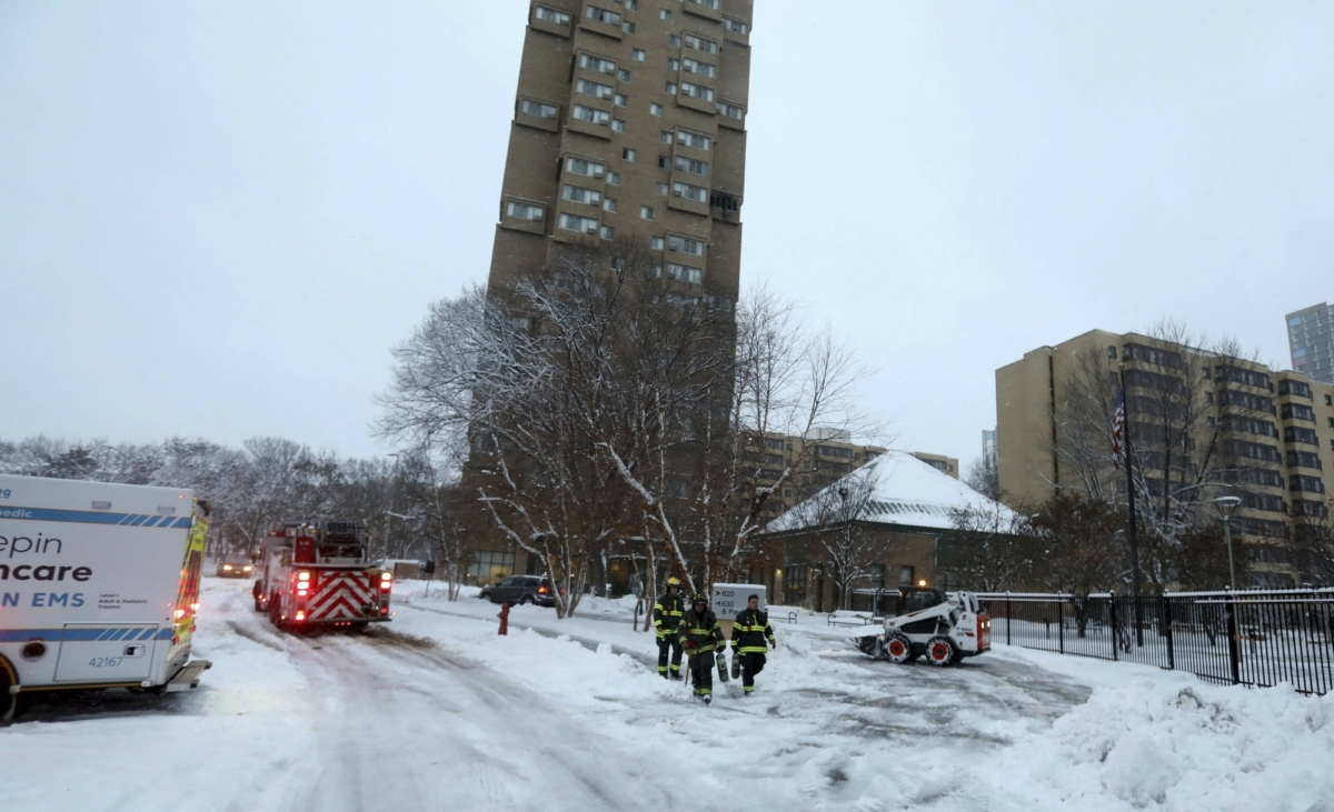 Minneapolis firefighters leave after a deadly fire at a high-rise apartment building, center in background on Nov. 27, 2019, in Minneapolis. (David Joles/Star Tribune via AP)