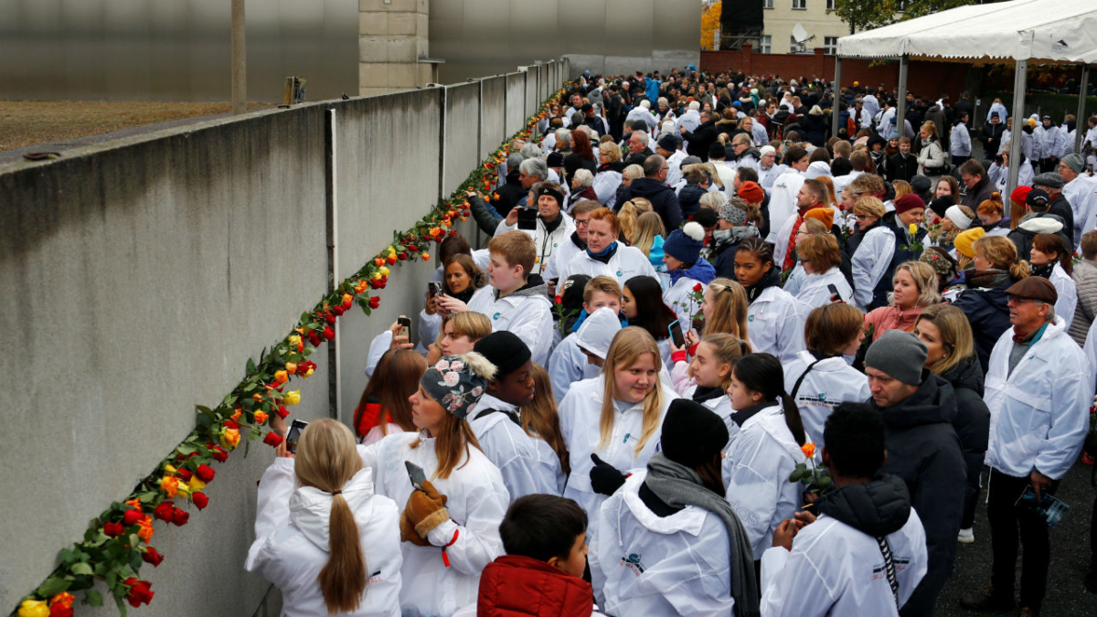 People place roses into a gap at the Wall memorial during a ceremony marking the 30th anniversary of the fall of the Berlin Wall at Bernauer Strasse in Berlin, Germany on Nov. 9, 2019. (Fabrizio Bensch/Reuters)