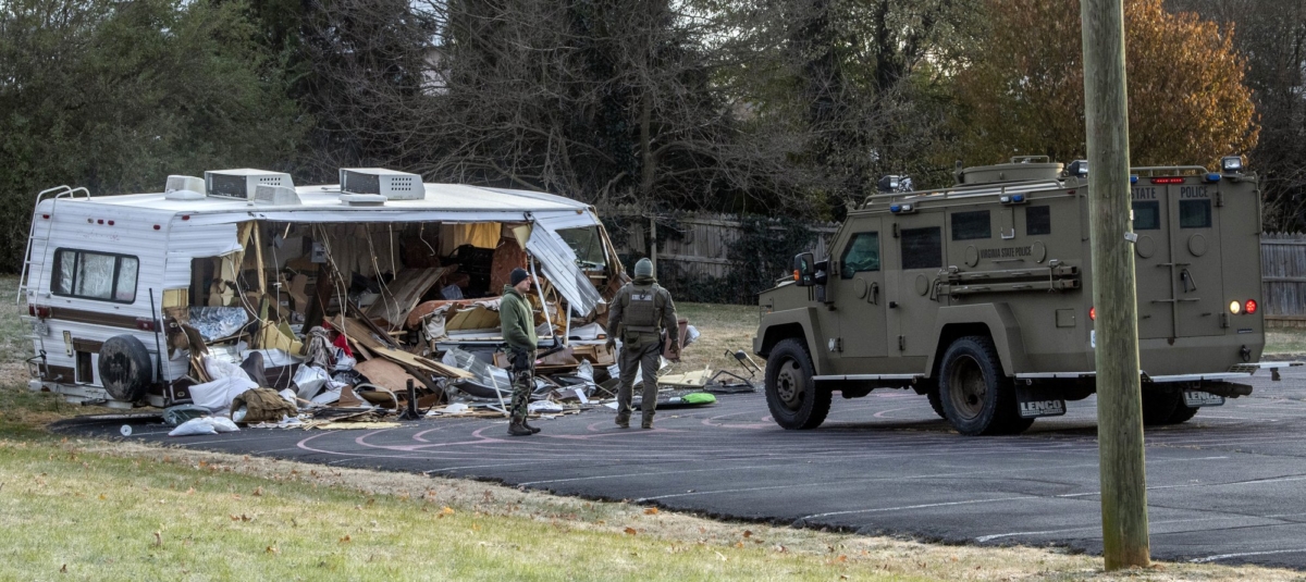 Police examine a stolen RV after ramming it multiple times with an armored vehicle, right, while searching for a Marine deserter who is wanted for questioning in a murder case, in Roanoke, Va. (Don Petersen/AP Photo)