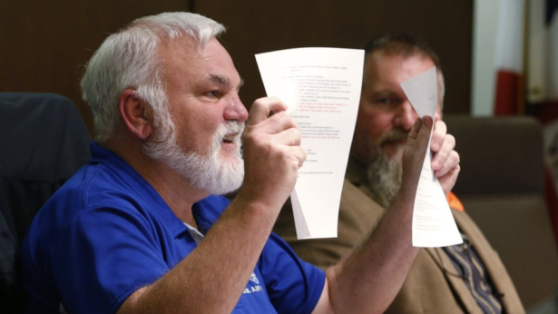 Chairman of the Buckingham County Board of Supervisors, Donald Bryan, holds up the Second Amendment Sanctuary during a meeting of the Board in Buckingham , Va., Dec. 9, 2019. (Steve Helber/AP Photo)