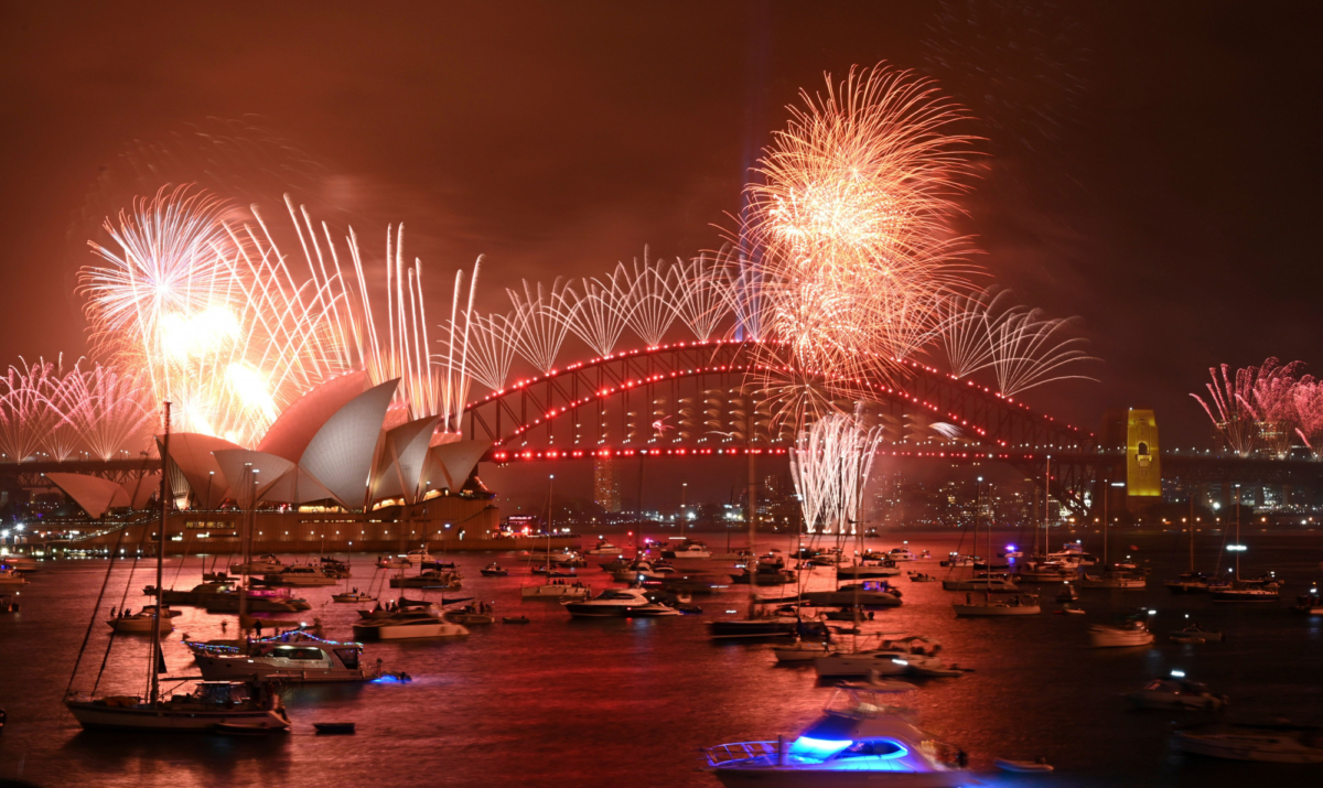 New Year's Eve fireworks erupt over Sydney's iconic Harbour Bridge and Opera House (L) during the fireworks show on Jan. 1, 2020. (Peter Parks/AFP via Getty Images)