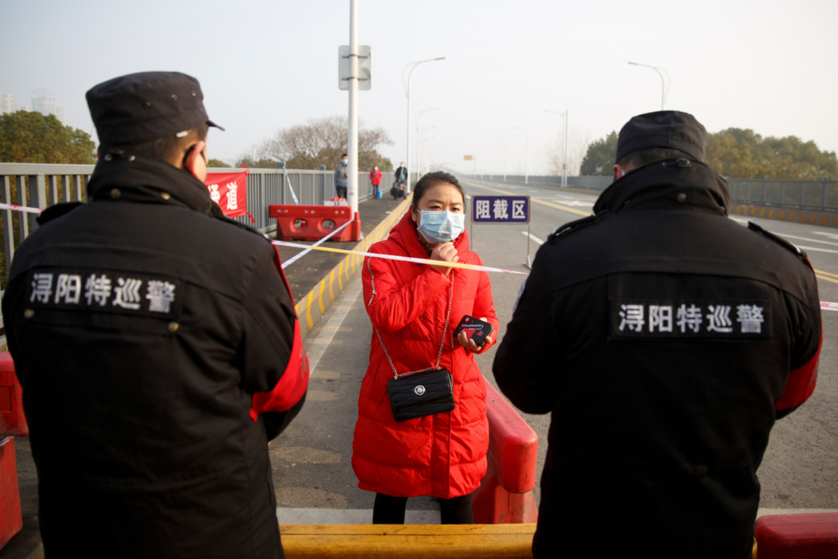 A woman who arrived from Hubei province talks to security personnel at the Jiujiang Yangtze River Bridge in an attempt to cross at a checkpoint in Jiujiang, Jiangxi province, China, as the country is hit by an outbreak of a new coronavirus, on Jan. 31, 2020. (Thomas Peter/Reuters)
