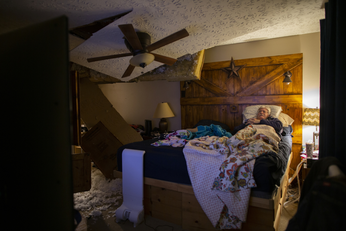 Lee Brewer watches the news from his bedroom as the ceiling hangs after it was damaged by a massive explosion in west Houston on Jan. 24, 2020, in Houston. (Marie D. De Jesús/Houston Chronicle via AP)