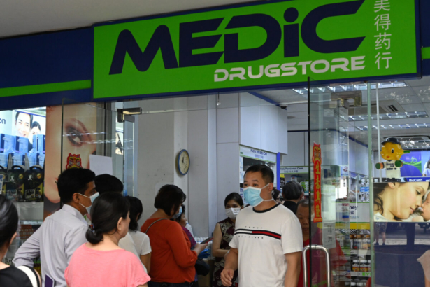 People queue outside a pharmacy to purchase protective face mask, thermometer and hand sanitizer in Singapore on January 29, 2020. (Roslan Rahman/AFP via Getty Images)