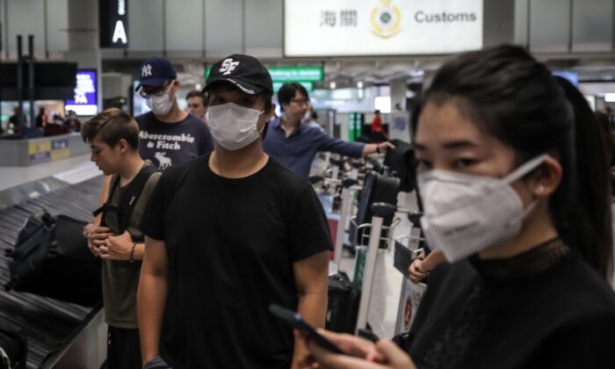Travelers wearing face masks as a precautionary measure to protect against the outbreak of coronavirus, at Hong Kong International Airport, on Jan. 23, 2020. (Vivek Prakash/AFP via Getty Images)