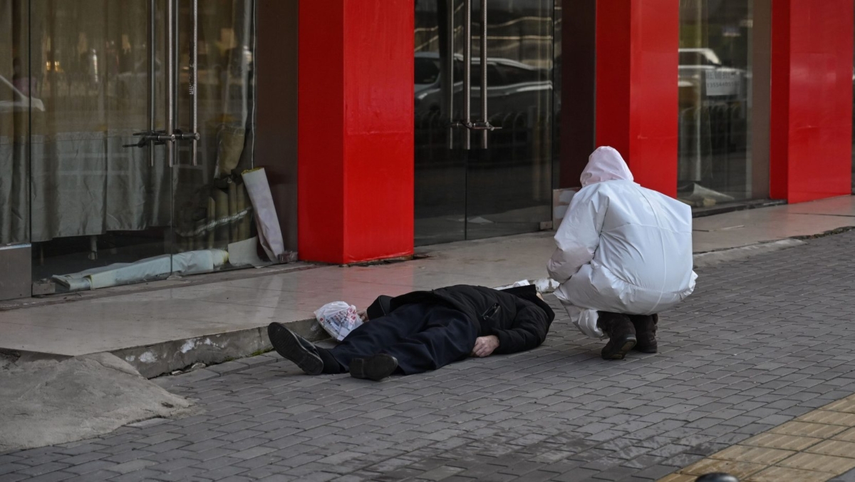 An elderly man wearing a facemask lies dead on the pavement after he collapsed along a street near a hospital in Wuhan, China, on Jan. 30, 2020. (Hector Retamal/AFP via Getty Images)