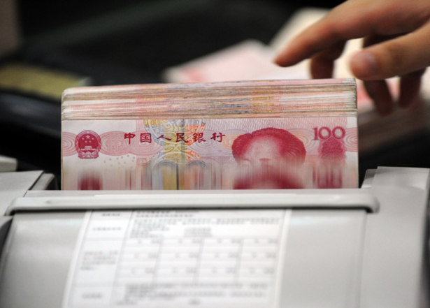 A Chinese bank clerk uses a machine to count the stacks of 100 yuan notes for a customer at a bank in Hefei, Anhui Province, China on Oct. 14, 2010. (STR/AFP/Getty Images)