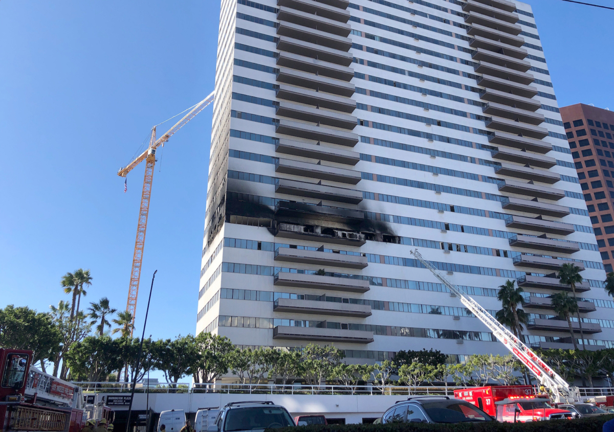 A Los Angele Fire Department ladder stands at the side of a 25-story high-rise apartment building where a fire broke out on a sixth-floor balcony and sent choking smoke billowing through the upper levels in West Los Angeles on Jan. 29, 2020. (Stafanie Dazio/AP Photo)