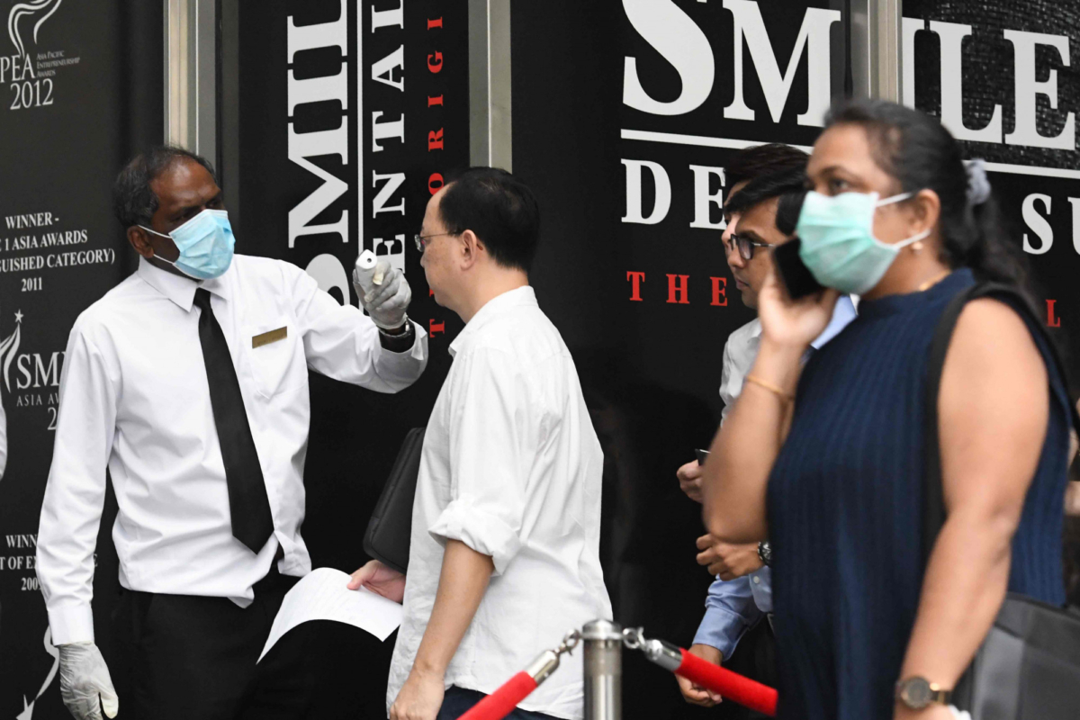 Building management staff conduct temperature screenings of visitors and tenants of a building in the financial district of Singapore, Singapore, on Feb. 10, 2020. (Roslan Rahman/AFP via Getty Images)