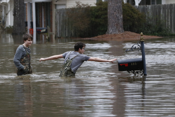 Blaine Henderson (R) reaches to tag a mailbox as Pearl River as he and his friend Jonah Valdez, play in the floodwaters of this northeast Jackson neighborhood, Miss., on Feb. 16, 2020. (Rogelio V. Solis/AP Photo)