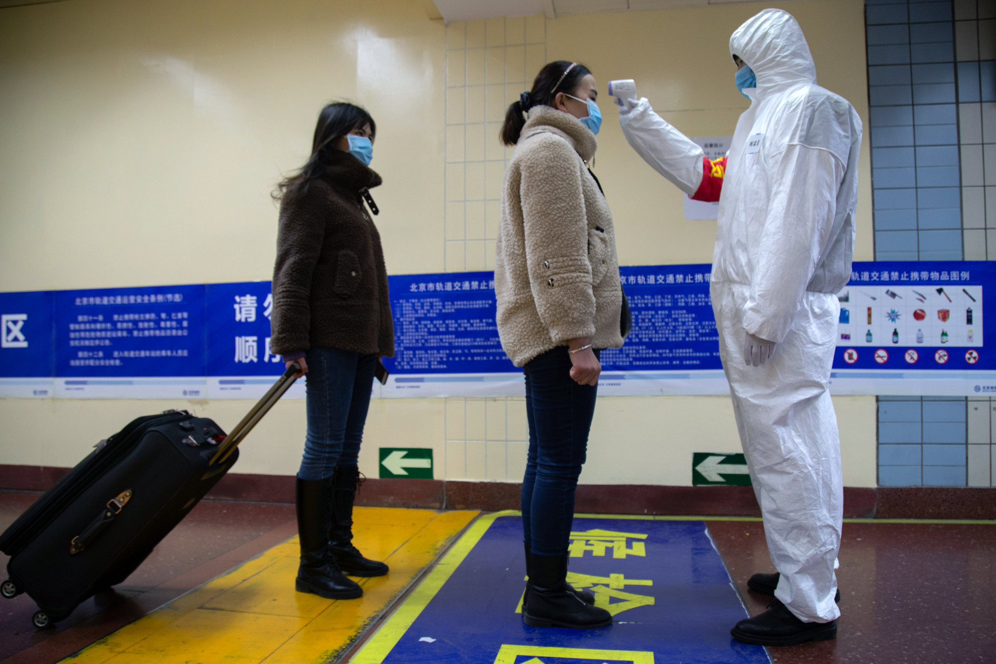 A health worker checks the temperature of women entering the subway in Beijing, China, on Jan. 26, 2020. (Betsy Joles/Getty Images)