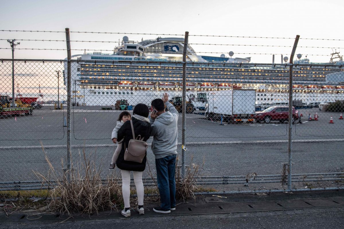 People wave to family members on board the Diamond Princess cruise ship as it sits docked at Daikoku Pier where it is being resupplied and newly diagnosed coronavirus cases taken for treatment as it remains in quarantine after a number of the 3,700 people on board were diagnosed with coronavirus, in Yokohama, Japan, on Feb. 11, 2020. (Carl Court/Getty Images)