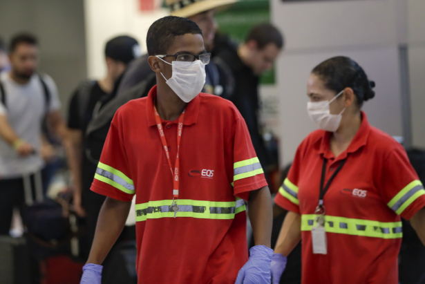 Airport employees wear masks as a precaution against the spread of COVID-19 as they work at the Sao Paulo International Airport in Sao Paulo, Brazil, on Feb. 26, 2020. (Andre Penner/AP Photo)
