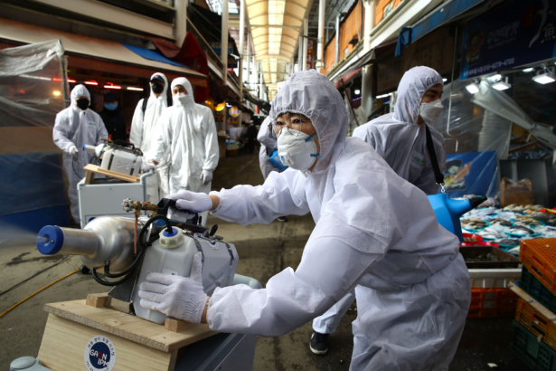 Disinfection personnel wearing protective gear spray anti-septic solution against the coronavirus (COVID-19) at a traditional market in Seoul on Feb. 26, 2020. (Chung Sung-Jun/Getty Images)