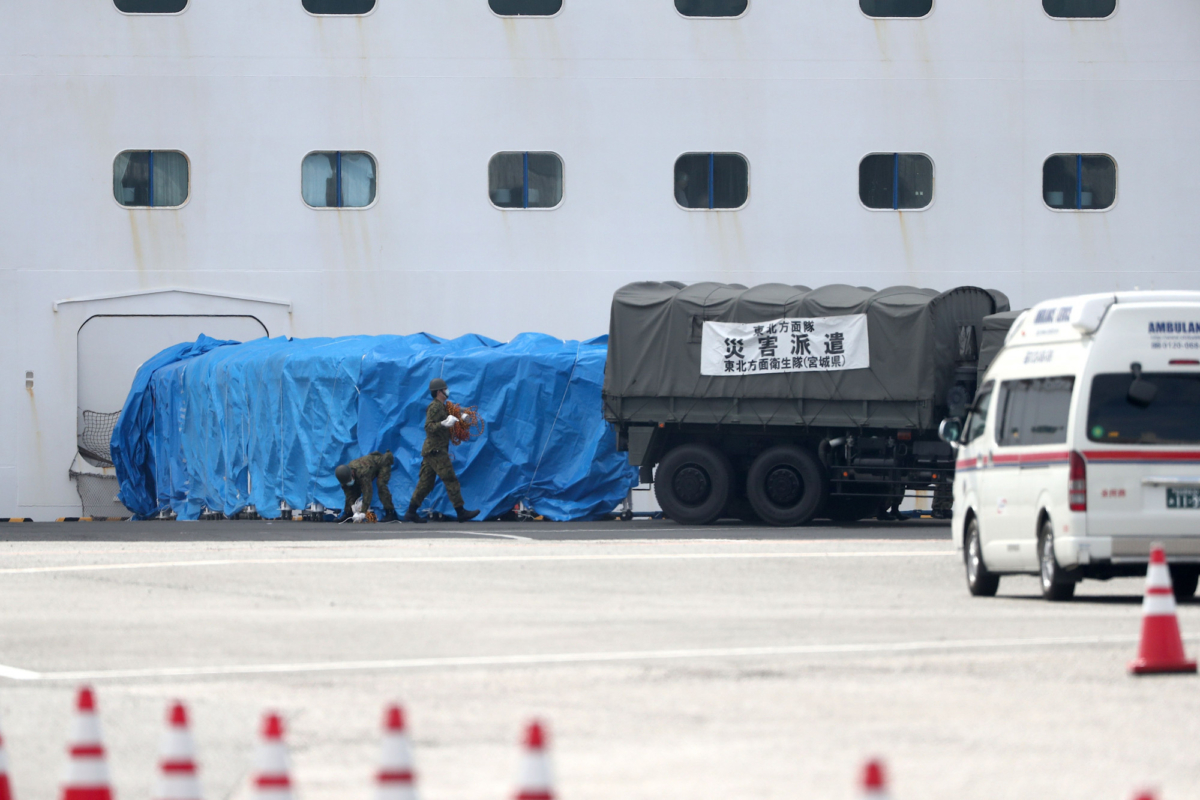 Members of the Japan Self-Defense Force attach a military vehicle to a gate of the Diamond Princess cruise ship, with around 3,600 people quarantined onboard due to fears of coronavirus, at the Daikaku Pier Cruise Terminal in Yokohama port, Japan, on 12, 2020. (BEHROUZ MEHRI/AFP via Getty Images)