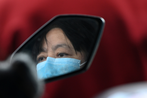 A passenger wearing a face mask is reflected on a motorcycle's side mirror as she rides a boat crossing the Yangtze river to Jiangzhou township in Jiujiang, Chinas central Jiangxi province, China, on March 14, 2020.
