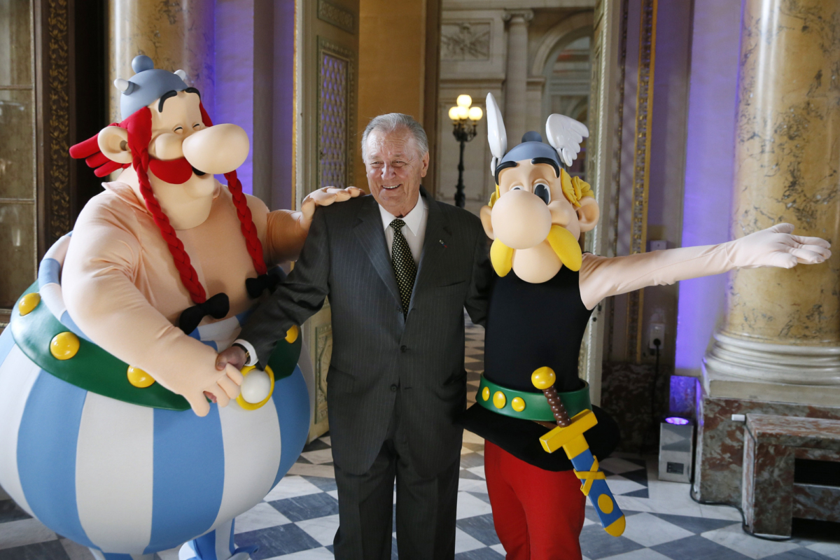 French cartoon artist Albert Uderzo poses with people dressed as Asterix (R) and Obelix during a press conference at the Monnaie de Paris where a new series of twelve coins illustrated with Asterix designs entitled "Asterix and the values of the Republic" was presented in Paris on March 25, 2015. (Photo by Patrick Kovarik/AFP via Getty Images)
