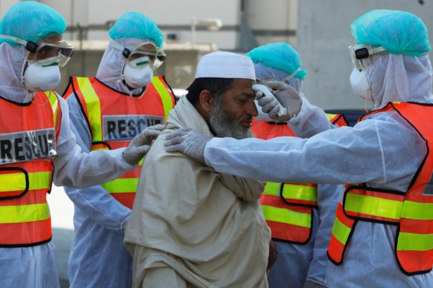 Rescue workers wearing masks and protective clothing check a man's temperature during a mock drill on handling suspected carriers of coronavirus, in Peshawar, Pakistan, on March 2, 2020. (Fayaz Aziz/Reuters)