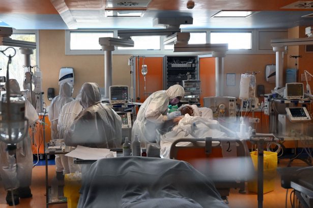 A medical worker in protective gear tends to a patient at a hospital on March 24, 2020. (Alberto Pizzoli/AFP/Getty Images)