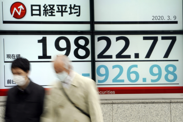 Men walk past an electronic stock board showing Japan's Nikkei 225 index at a securities firm in Tokyo, Japan, on March 9, 2020. (Eugene Hoshiko/AP Photo)