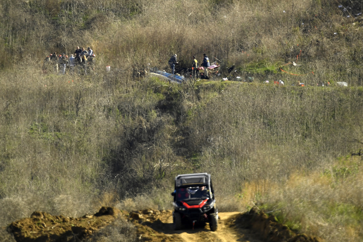 Investigators, top, work the scene of a helicopter crash that killed former NBA basketball player Kobe Bryant, his 13-year-old daughter, Gianna, and seven others as Los Angeles County Sheriff’s deputies patrol in an all-terrain vehicle on a hillside in Calabasas, Calif., on Jan. 27, 2020. (Mark J. Terrill/AP Photo)
