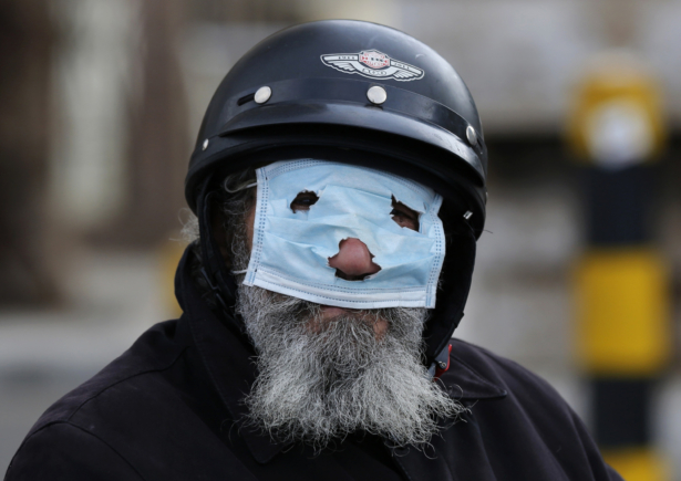 A man with a motorcycle helmet covers his face with a mask in Beirut, Lebanon, on March 15, 2020. (Hussein Malla/AP Photo)