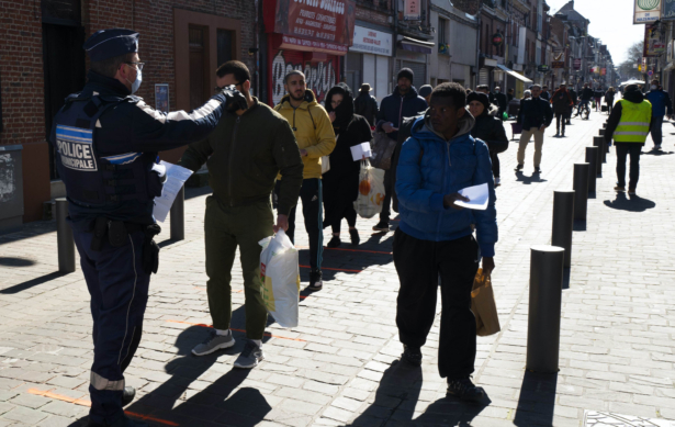A city police officer checks residents at an open air market in Lille, France, on March 22, 2020. (Michel Spingler/AP Photo)