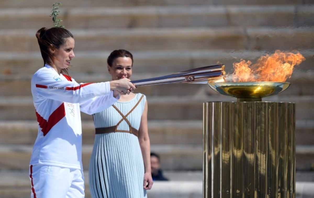 An athlete lights the Olympic torch during the olympic flame handover ceremony for the 2020 Tokyo Summer Olympics, in Panathenaic Stadium, Athens, Greece, on March 19, 2020. (Aris Messinis/Pool via Reuters)