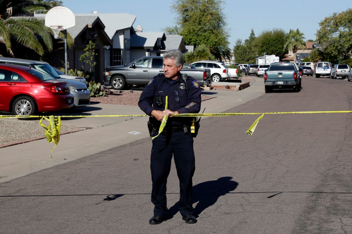 A Phoenix police officer connects crime scene tape together outside the scene of a deadly shooting, in Phoenix, on March 30, 2020. (Matt York/AP Photo)