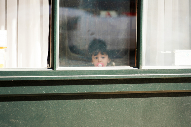 A child with a pacifier looks out a window as the CCP virus continues to spread across the United States, in New York City on March 24, 2020. (Cindy Ord/Getty Images)
