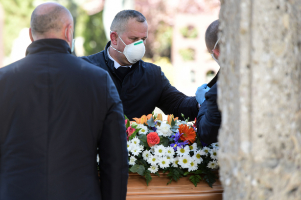 Undertakers wearing a face mask unload a coffin out of a hearse at the Monumental cemetery of Bergamo, Lombardy, Italy, on March 16, 2020. (Pierco Cruiciatti/AFP via Getty Images)