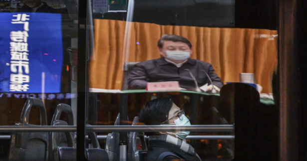 A large screen in the showing Chinese leader Xi Jinping wearing a protective mask during his visit to Wuhan earlier in the day, the epicentre of the coronavirus, on CCTV's evening newscast is reflected in a bus window as it passes by in Beijing, China, on March 10, 2020. (Kevin Frayer/Getty Images)