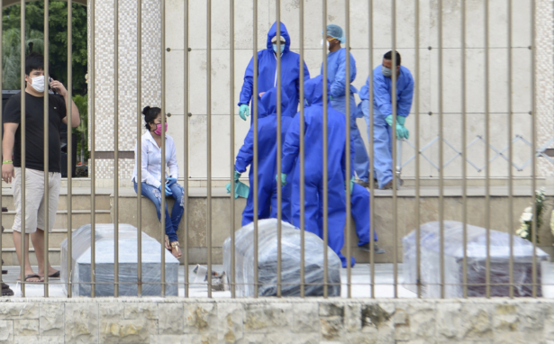 Relatives and the staff of Jardines de la Esperanza cemetery wait to bury suspected victims of the CCP virus, in coffins which authorities have wrapped with plastic, in Guayaquil, Ecuador, on April 1, 2020. (Andrea Aguilar/AP Photo)