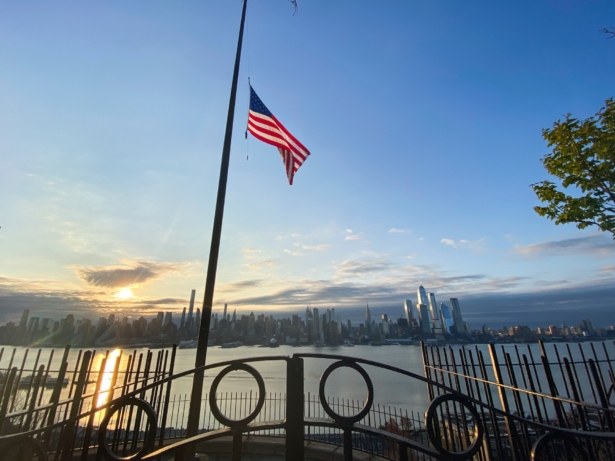 Flags are flying at half-mast as the sun rises behind in Manhattan as seen from Weehawken, New Jersey, on April 6, 2020. (Kena Betancur/Getty Images)