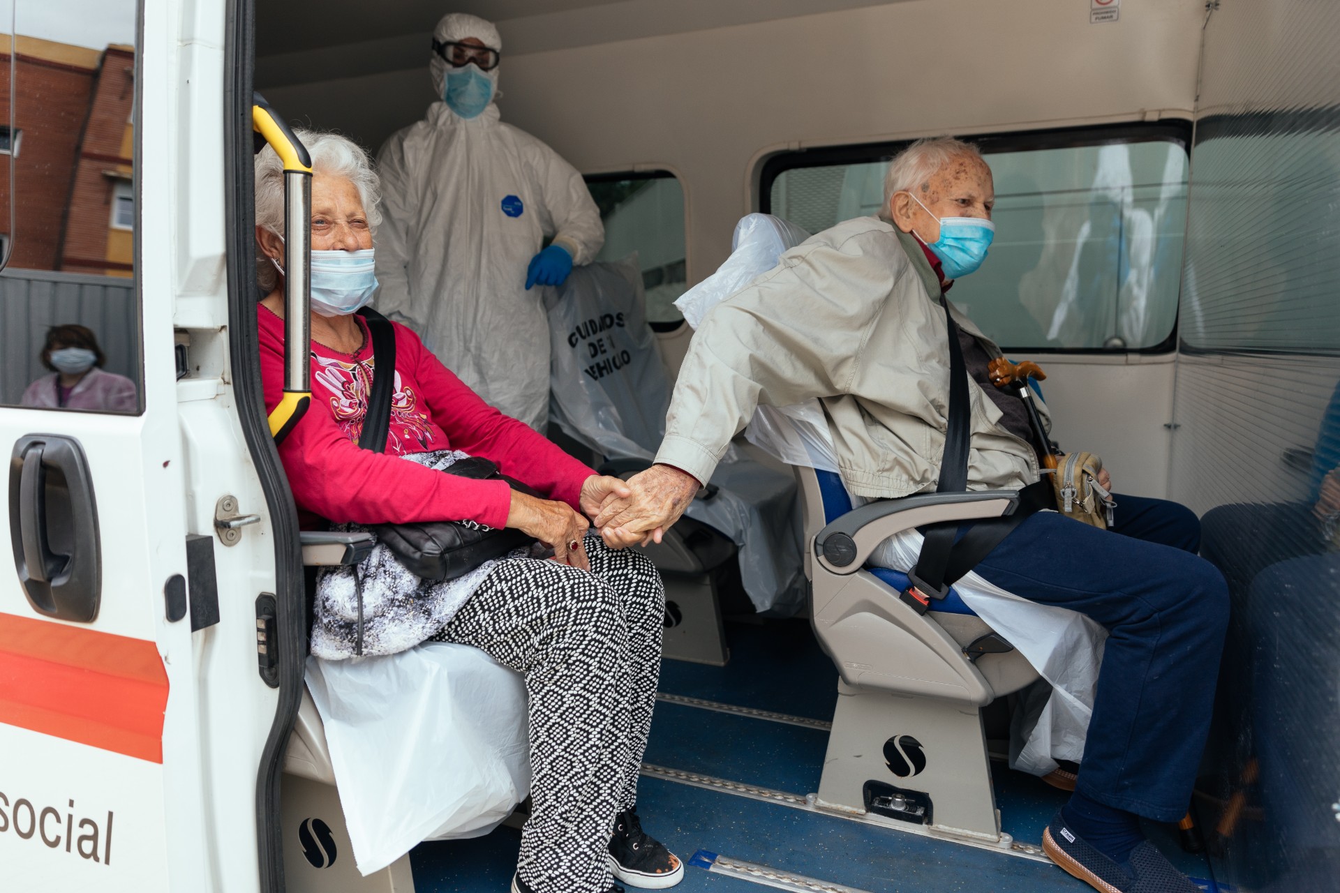 Two elderly people infected with COVID-19 hold hands while being transported by Red Cross volunteers from the Pyrenees residence to another residence where there are only infected with CCP virus in Zaragoza, Spain, on April 28, 2020. (Alvaro Calvo/Getty Images)