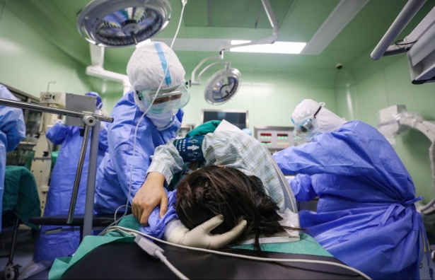A doctor comforts a pregnant woman infected by the CCP virus before her cesarean section at a gynecology and obstetrics isolation ward in Xiehe hospital in Wuhan, China, on March 7, 2020. (STR/AFP/Getty Images)
