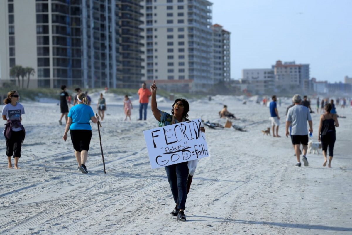 A person carries a sign at the beach in Jacksonville Beach, Fla., on April 17, 2020. (Sam Greenwood/Getty Images)