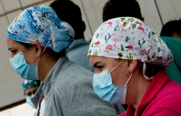 Healthcare workers wearing face masks observe three minutes of silence in memory of COVID-19 victims outside La Fe hospital in Valencia, Spain, on April 19, 2020. (Jose Jordan/AFP via Getty Images)