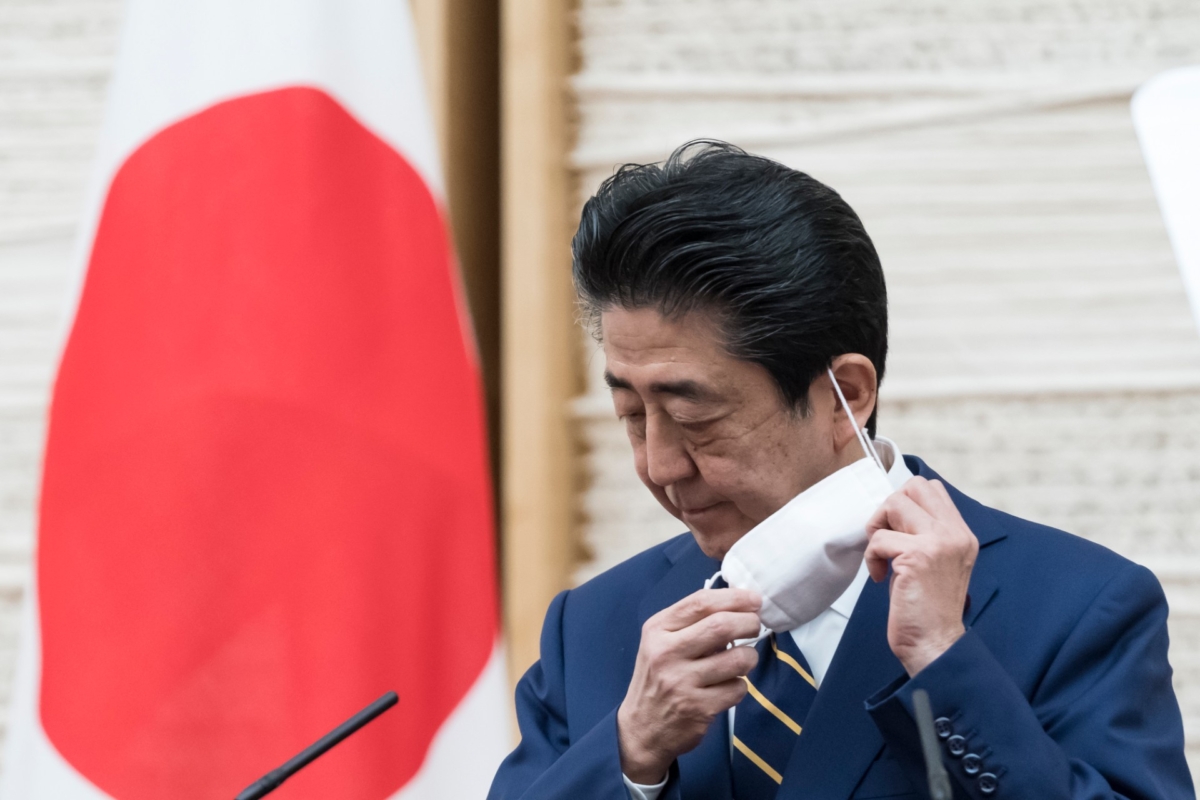 Japan's Prime Minister Shinzo Abe removes his face mask during a press conference at the prime minister's official residence in Tokyo, Japan, on April 7, 2020. (Tomohiro Ohsumi/Getty Images)