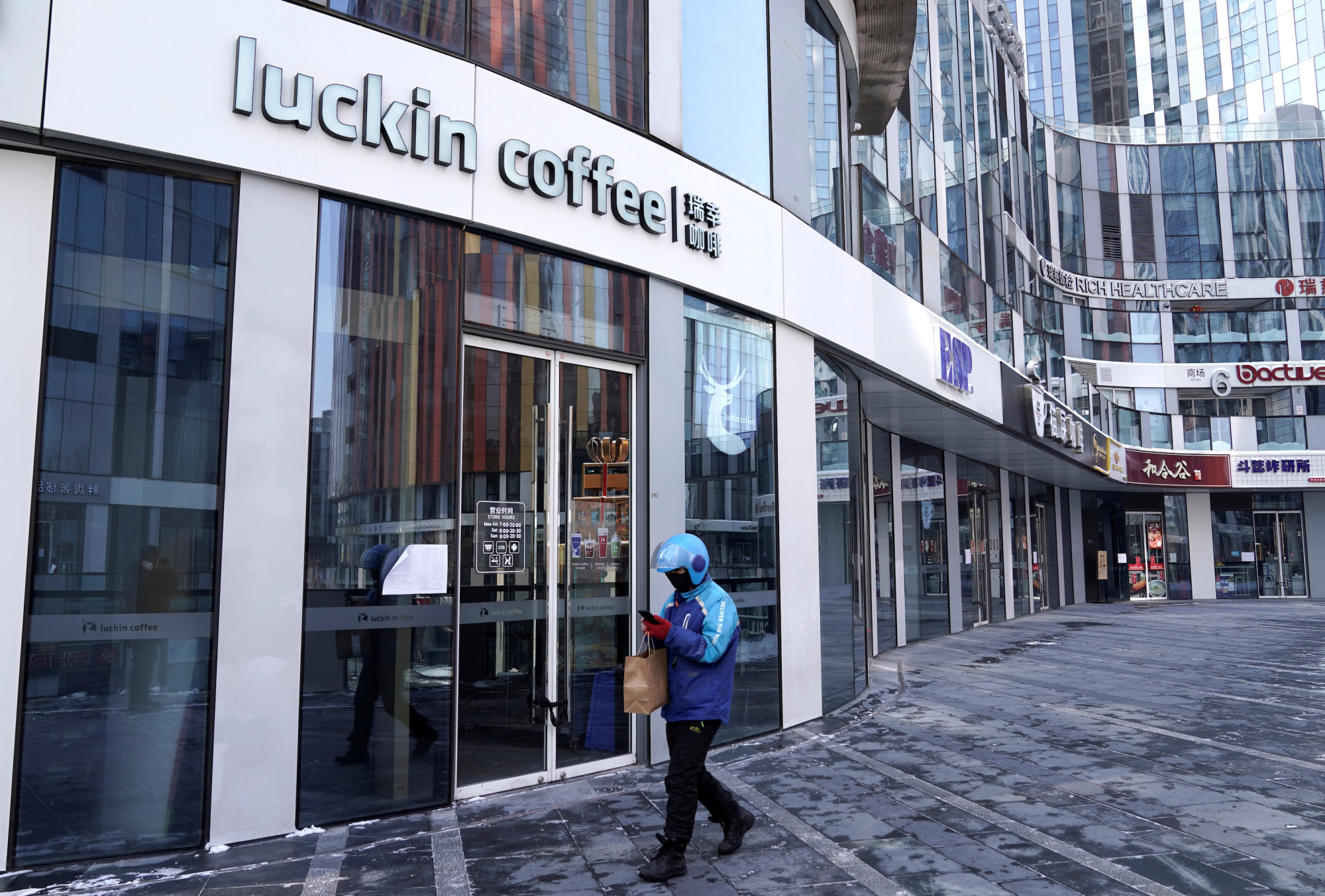 A deliveryman walks past a closed Luckin Coffee store at Sanlitun, as the country is hit by an outbreak of the CCP virus, in Beijing, China, on Feb. 7, 2020. (Jason Lee/Reuters)